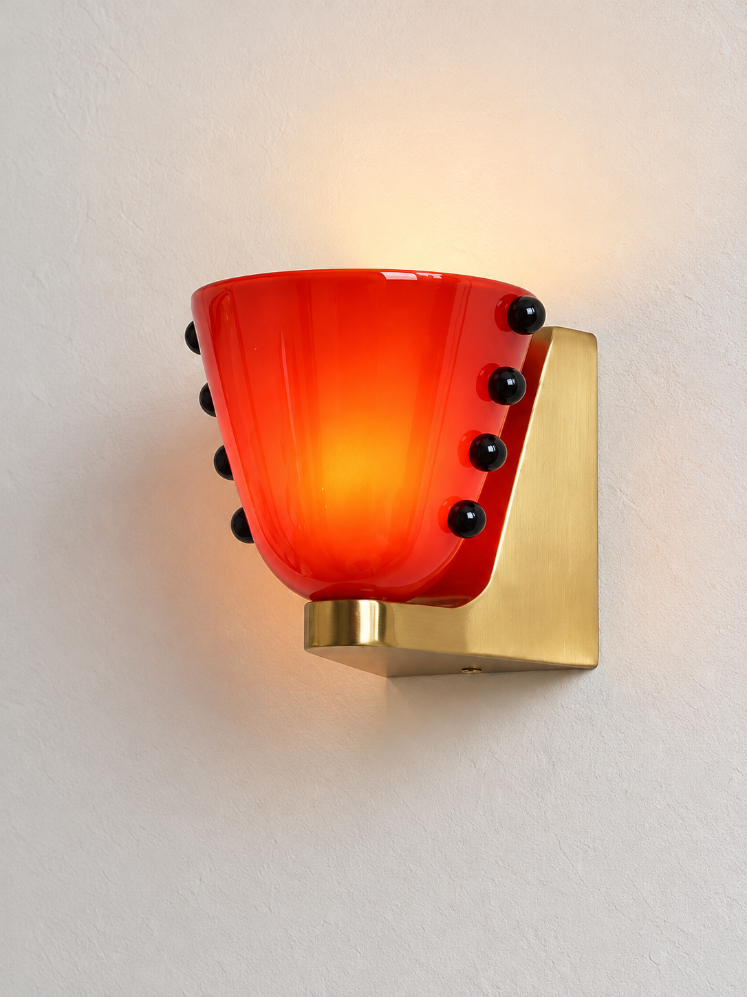 Red glass cup wall light with black bead details and copper-tone mount