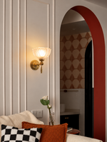 Copper-tone floral glass wall light beside a living room arch