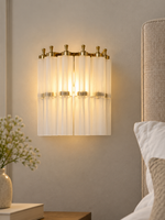 Fluted Glass Column Wall Sconce in Frosted White beside a linen bedroom headboard