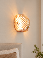 Spiral glass wall sconce in Cognac with chrome mounting hardware on an ivory bedroom wall