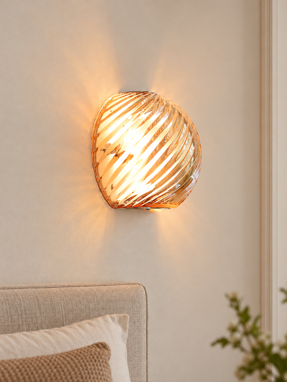 Spiral glass wall sconce in Cognac with chrome mounting hardware on an ivory bedroom wall