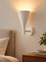 White plaster cone wall sconce in a warm bedroom