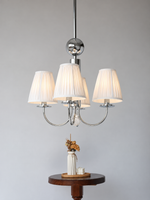 Four-light pleated fabric chandelier above a small wooden table