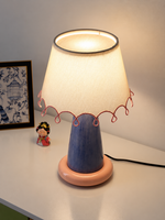 Elevated view of the illuminated ivory fabric shade and pink loop trim
