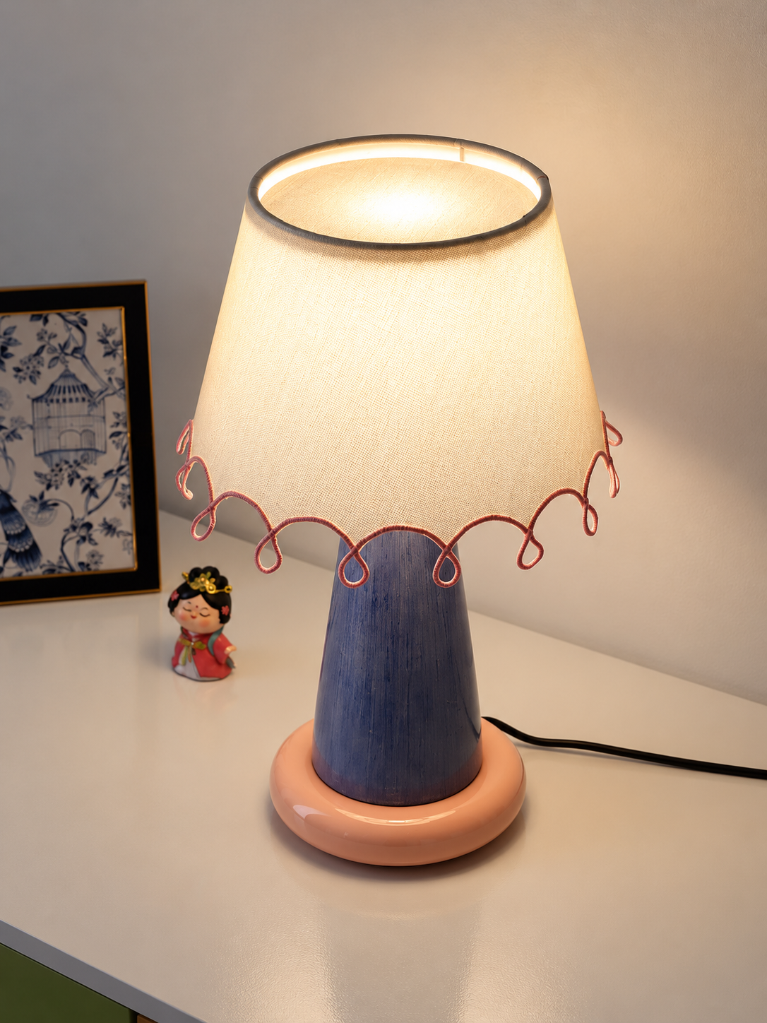 Elevated view of the illuminated ivory fabric shade and pink loop trim