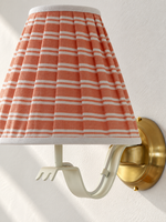 Close-up of coral and white striped fabric shade and ivory curved iron arm